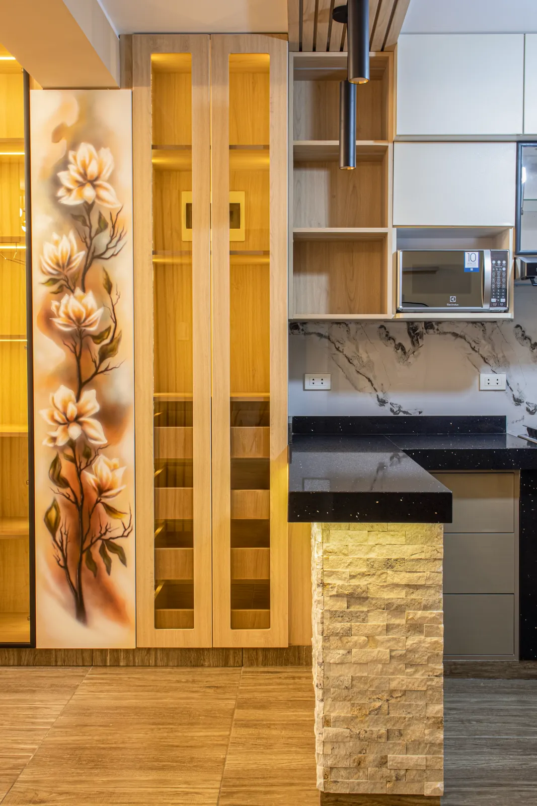 Vitrina de madera iluminada junto a un panel decorativo floral y barra enchapada en piedra — Santiago de Surco