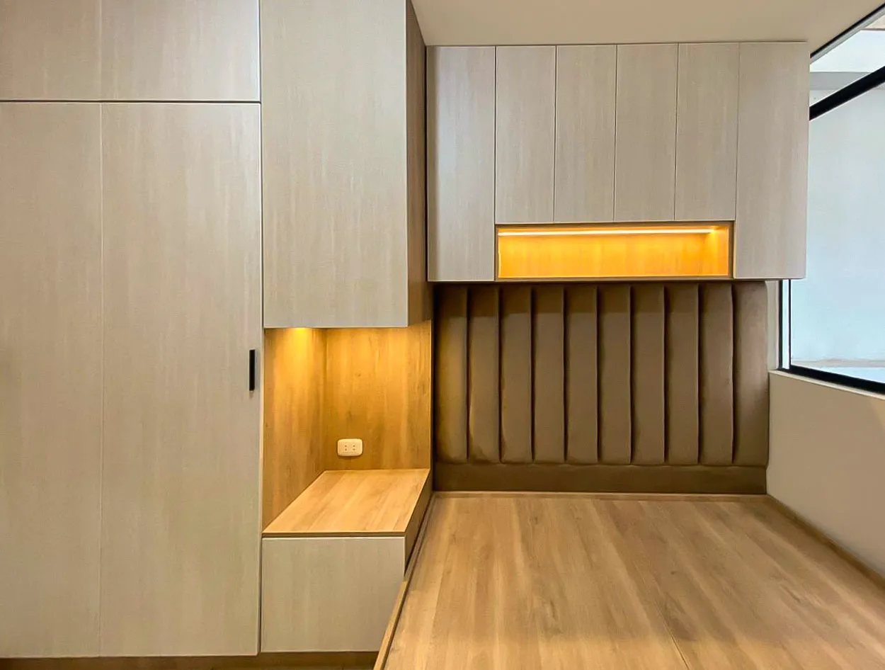 Banca de madera integrada bajo un nicho con luz LED cálida y panel de listones verticales — Santiago de Surco