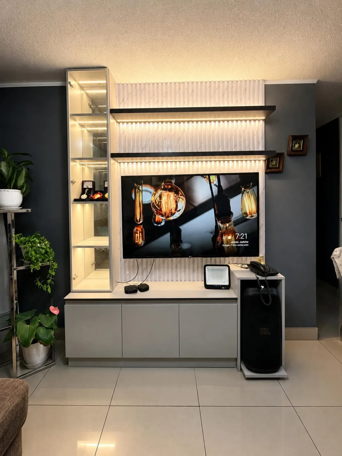 Render 3D de una sala con mueble de TV gris perla, repisas de madera con luz cálida y cava de vino